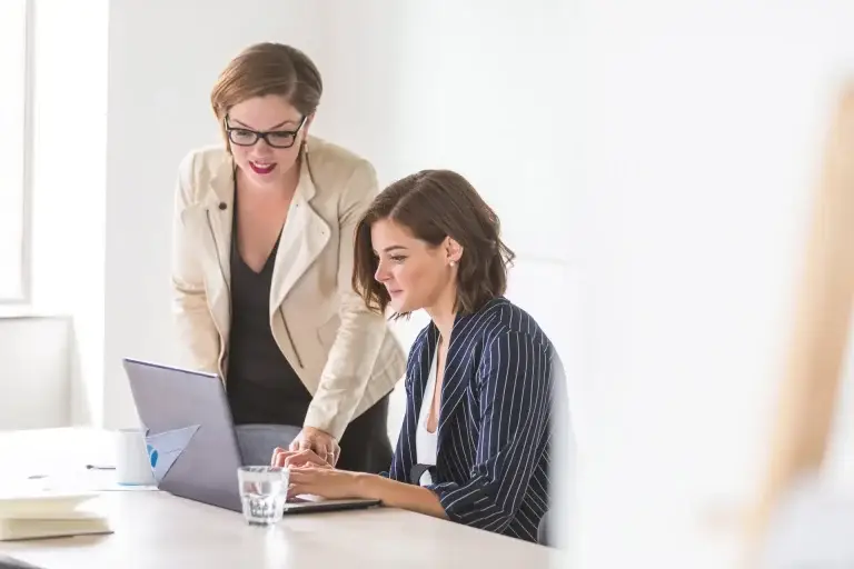 2 women at a desk looking at a laptop